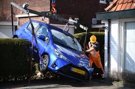 Automobilist rijdt per ongeluk achteruit en komt met voertuig vast in heg te zitten