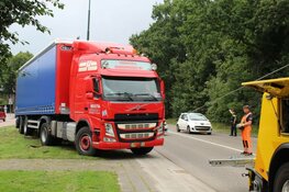 Vrachtwagen rijdt zich vast in het gras in Huizen