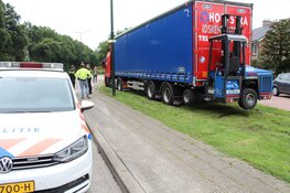 Vrachtwagen rijdt zich vast in het gras in Huizen