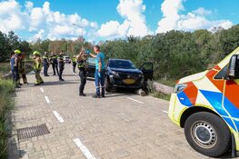 Auto rijdt over boomstammen in Bussum, bestuurder nagekeken door ambulancepersoneel