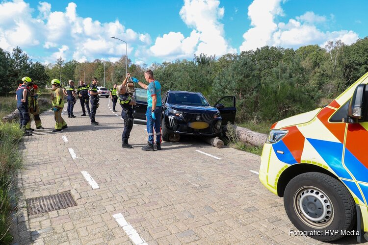 Auto rijdt over boomstammen in Bussum, bestuurder nagekeken door ambulancepersoneel