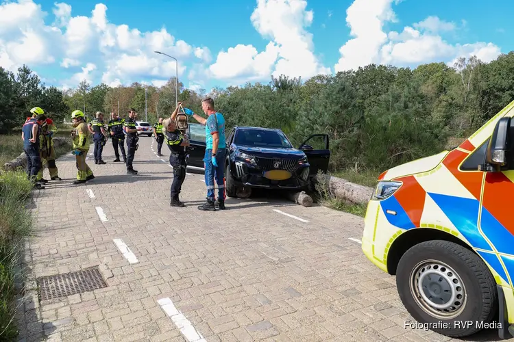 Auto rijdt over boomstammen in Bussum, bestuurder nagekeken door ambulancepersoneel