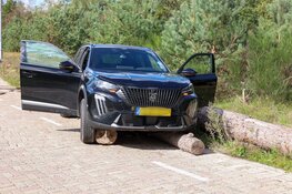 Auto rijdt over boomstammen in Bussum, bestuurder nagekeken door ambulancepersoneel