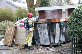 Grote bouwcontainer tegen woning in vlammen opgegaan