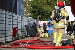 Brandweer haalt gasflessen uit brandende container